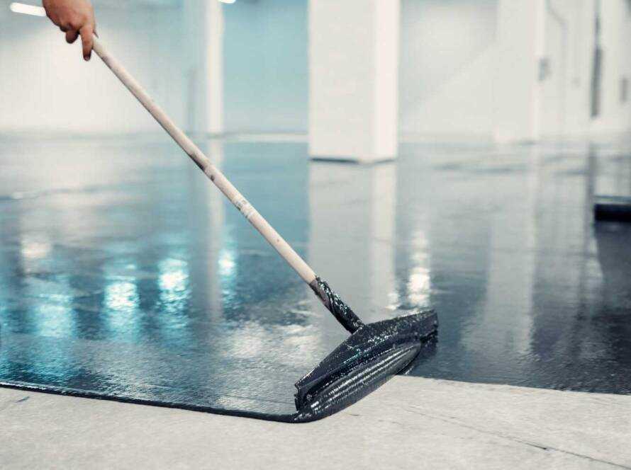 Worker applies gray epoxy reisin to a new floor. Modern Surface